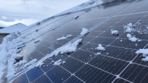 A bit of snow and ice covering solar panels on the roof of a house